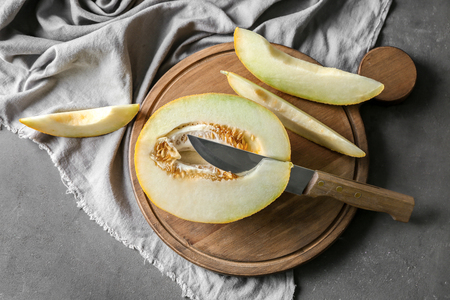 Wooden board with yummy melon and knife on cooking tableの写真素材