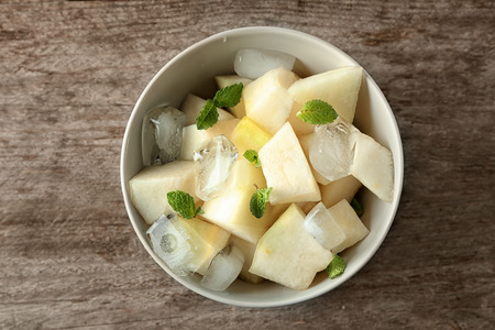 Bowl with yummy melon slices on wooden tableの写真素材