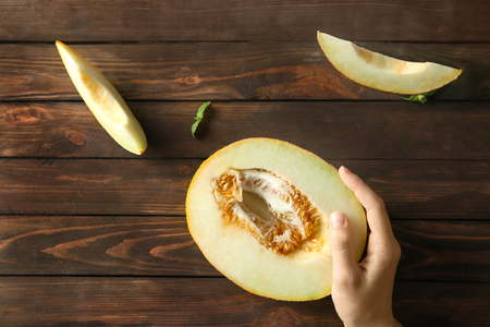 Young woman with yummy melon at wooden tableの写真素材