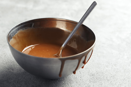Bowl with sweet caramel sauce on tableの写真素材