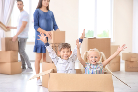 Happy siblings with parents having fun in their new homeの写真素材