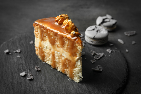 Slate plate with piece of delicious caramel cake on tableの写真素材