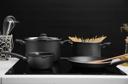 Different cooking utensils on electric stove against black backgroundの写真素材