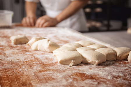 Raw buns on table and man in bakeryの写真素材