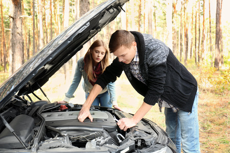 Young couple near damaged car in forestの写真素材