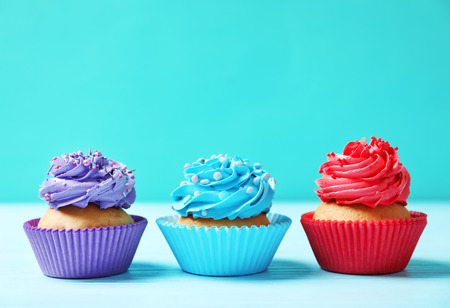Tasty cupcakes on table against color backgroundの写真素材