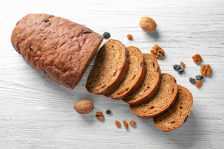 Yummy fresh bread with walnut and raisins on wooden background