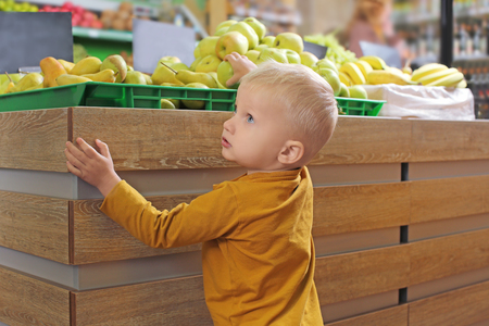 Cute little boy choosing apples in supermarketの写真素材
