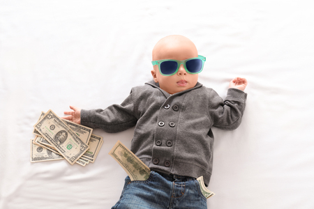 Cute boy with money on white bedsheetの写真素材