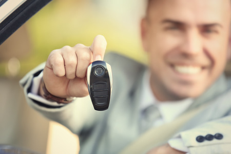 Man in formal wear holding car key on blurred background
