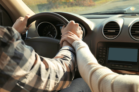 Young couple holding hands together in car