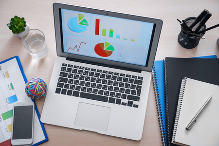 Workplace with laptop and diagrams on screen. Marketing concept