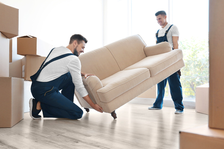 Delivery men moving sofa in room at new homeの写真素材