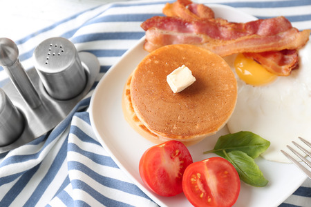 Tasty breakfast with pancakes, bacon and fried egg on plateの写真素材