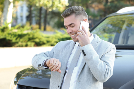 Man in formal wear talking on phone near car outdoorsの写真素材