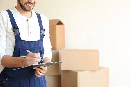 Delivery man checking list on clipboard indoorsの写真素材