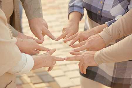 Senior people from care home putting hands together as symbol of unity outdoorsの写真素材
