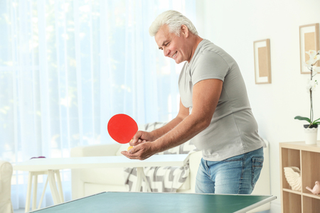 Senior man playing table tennis indoorsの写真素材