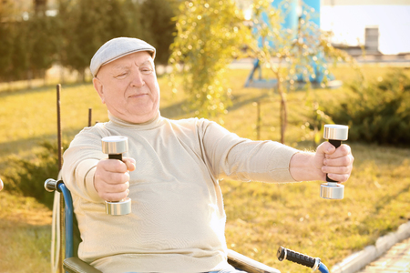 Senior man from care home doing exercise with dumbbells outdoorsの写真素材