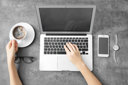 Woman using laptop on grey tableの写真素材