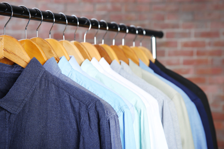 Male jackets and shirts hanging on clothing rail indoorsの写真素材