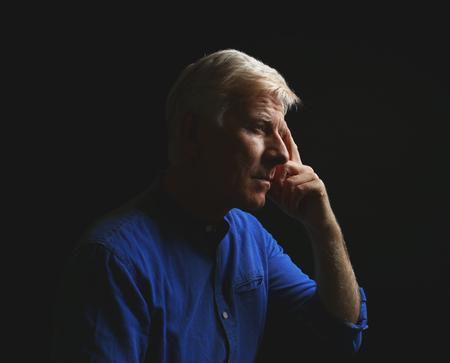 Portrait of thoughtful mature man on dark backgroundの写真素材