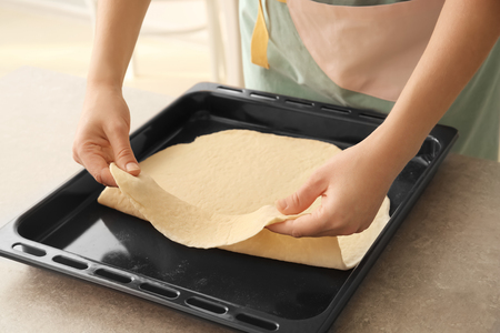 Woman putting puff pastry on baking trayの写真素材