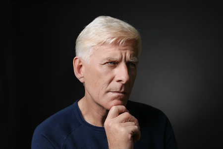 Portrait of thoughtful mature man on dark backgroundの写真素材