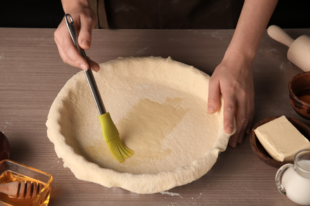 Woman spreading oil on puff pastry with brushの写真素材