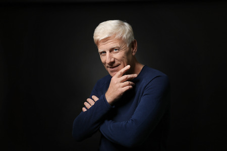 Portrait of handsome mature man on dark backgroundの写真素材