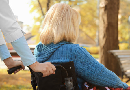 Disabled senior woman and young caregiver outdoorsの写真素材