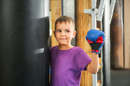 Cute little boy near punchbag in gymの写真素材