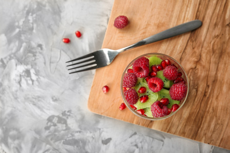 Board with jar of delicious fruit salad on table