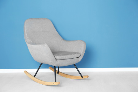 Comfortable rocking armchair on blue wall backgroundの写真素材
