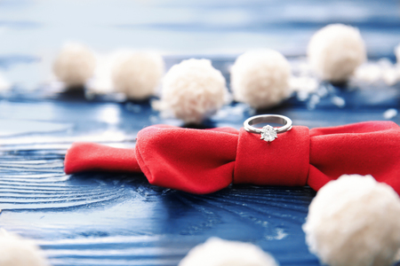 Engagement ring with red bow and treats on tableの写真素材