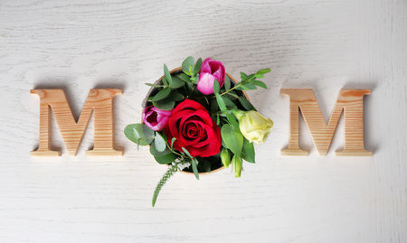 Word "Mom" and fresh flowers on light background. Mother's Day compositionの写真素材