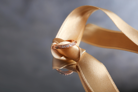 Ribbon with beautiful engagement ring on reflective surfaceの写真素材