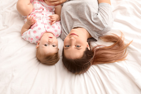 Young mother and her cute baby on bedの写真素材
