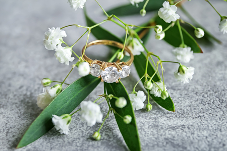 Beautiful engagement ring and flower on table, closeupの写真素材