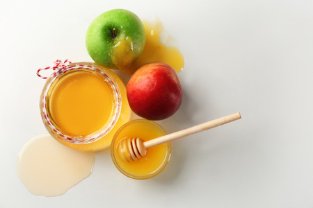 Gravy boat and jar with aromatic honey and apples on white backgroundの写真素材