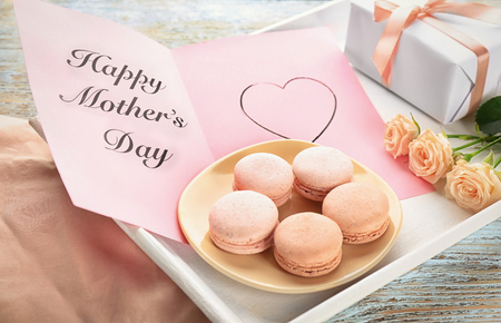 Delicious macaroons and greeting card with words "Happy Mother's day" on trayの写真素材