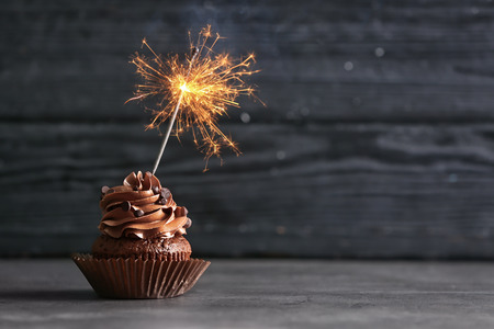 Tasty chocolate cupcake with sparkler on wooden backgroundの写真素材