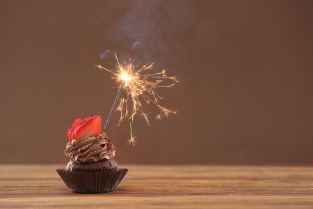 Tasty chocolate cupcake with sparkler on wooden tableの写真素材
