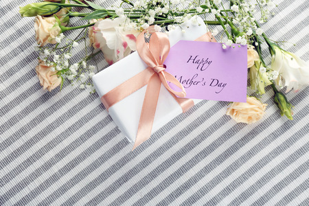 Card with words "Happy Mother's day", gift box and flowers on striped cloth, top viewの写真素材