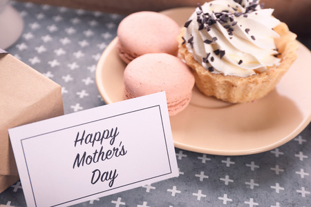 Card with words "Happy Mother's day" and tasty desserts on tableの写真素材