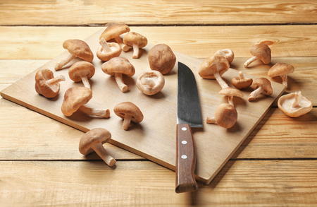 Board with raw shiitake mushrooms on wooden tableの写真素材