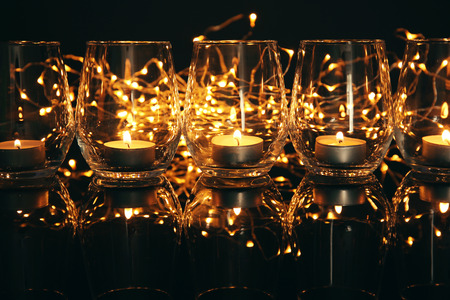 Glasses with burning candles on dark backgroundの写真素材