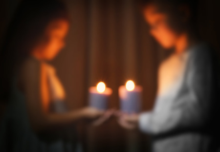 Blurred view of little children holding burning candles in darknessの写真素材