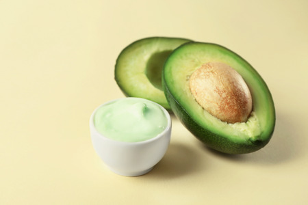 Bowl of body cream with avocado on color backgroundの写真素材