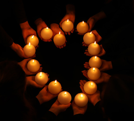 Young people with burning candles in darknessの写真素材